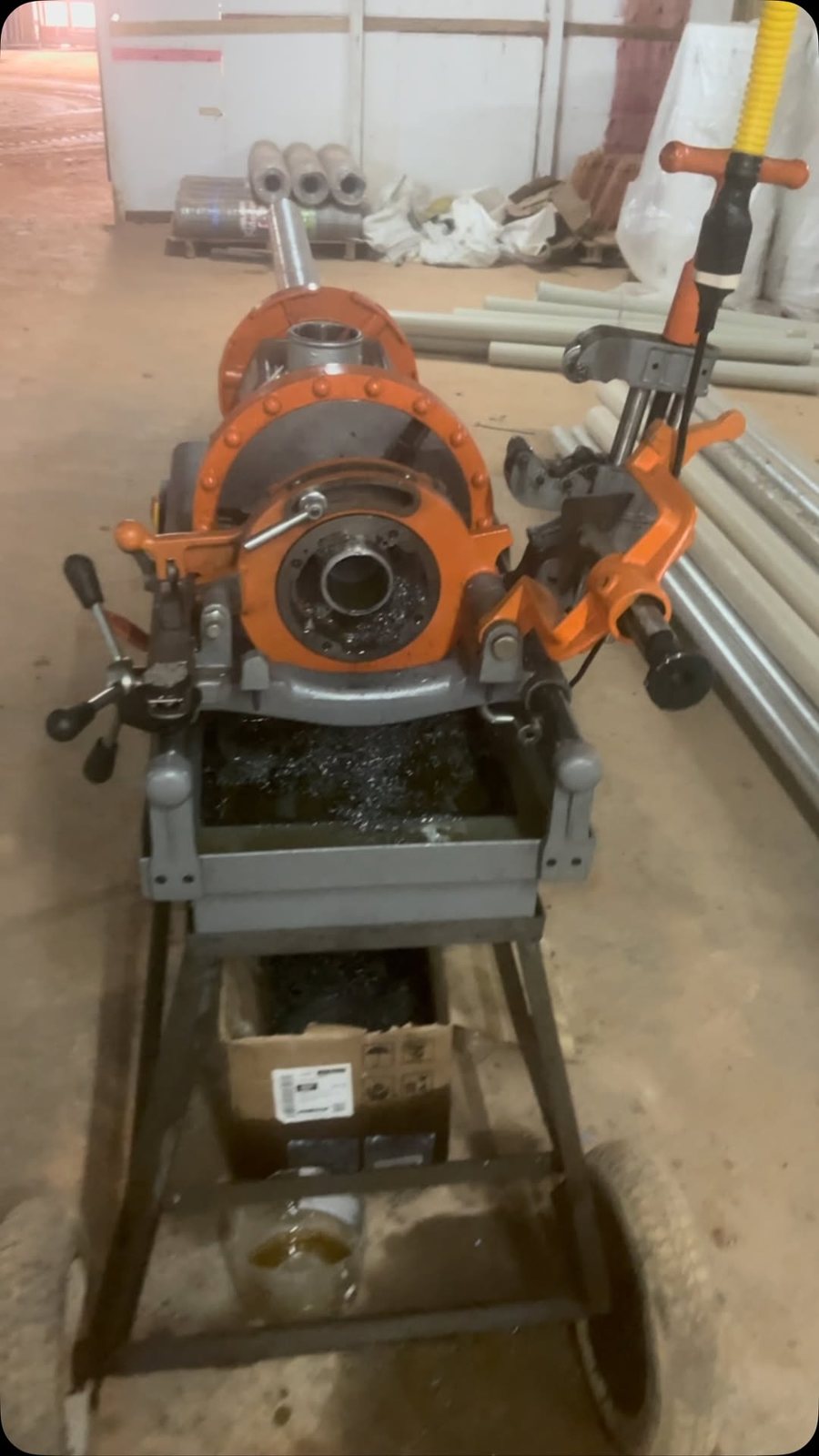 Máquina roscadora de tubos laranja sobre carro com rodas